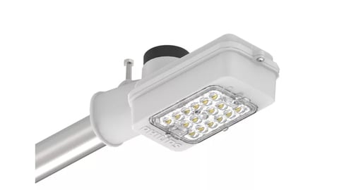 Modern LED street light fixture with white housing mounted on silver aluminum pole against light background